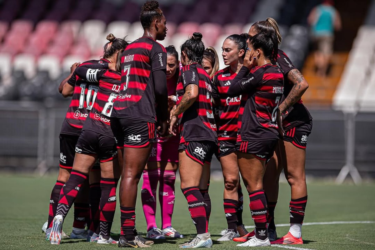 As atletas do Flamengo estão reunidas em uma rodinha, concentradas antes da partida