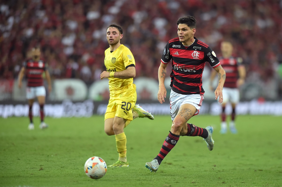Pedro Milans observa Ayrton Lucas correr com a bola em jogo entre Flamengo e Peñarol